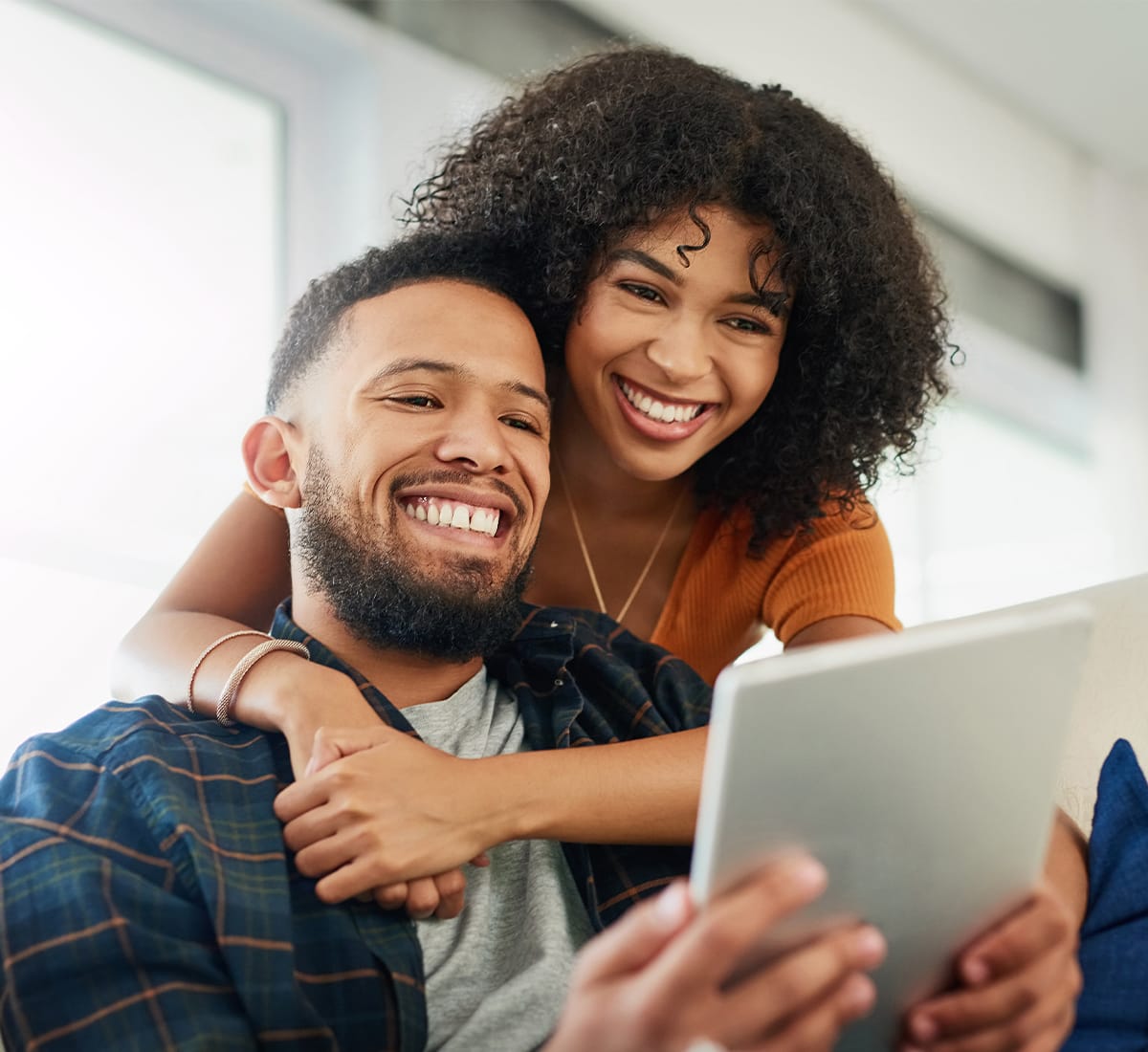 a couple sitting on a couch and looking into a laptop